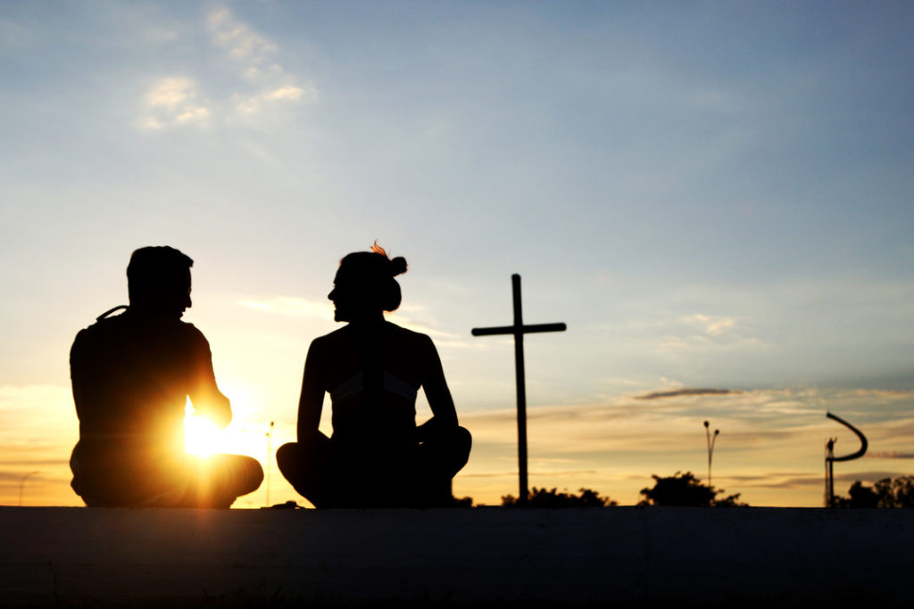 Casal admirando pôr do Sol com cruz e Memorial JK ao fundo